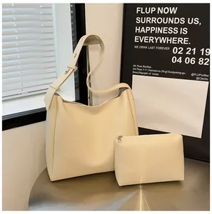 Detail shot of the cream faux leather tote bag and zipper pouch set on a metal table
