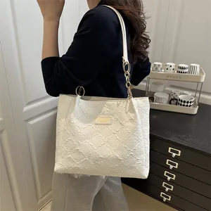 Minimalist white textured tote bag with leather handles shown on shoulder for daily commute