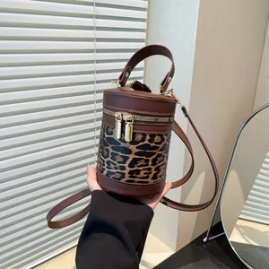 Detailed close-up of leopard print bucket bag featuring brown leather trim and metal zippers