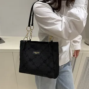 Minimalist black textured tote bag with golden chain strap for women's casual fashion
