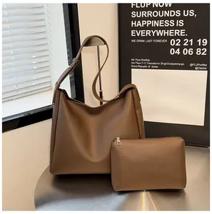 Detail of dark brown leather tote bag and matching pouch on a minimalist metal table