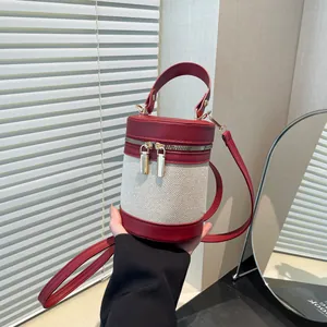 Detail of red leather and cream canvas bucket bag with gold dual zipper closure