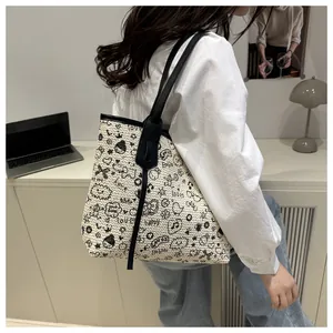 Detail of a woven tote bag featuring black graffiti patterns and dual shoulder straps