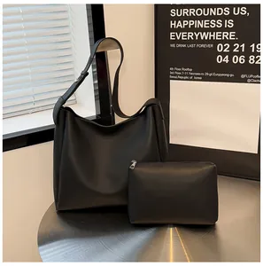 Detail view of black minimalist hobo bag and small pouch set on a stylish metal table