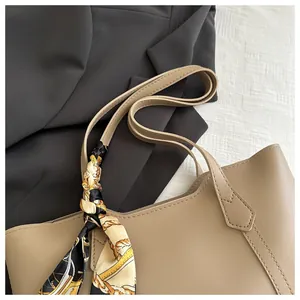 Detail of khaki tote bag with premium leather texture and patterned silk scarf decoration