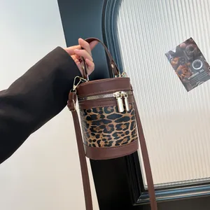 Detail of leopard print bucket bag with brown leather trim and golden hardware buckle