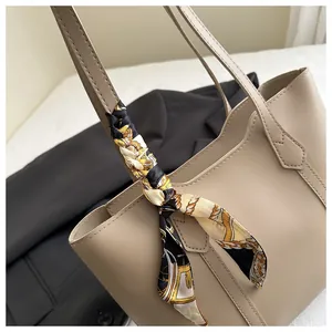 Close-up of beige leather tote bag featuring elegant equestrian print silk scarf handle