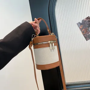 Detail of canvas bucket bag with contrast leather trim and dual metal zipper closure