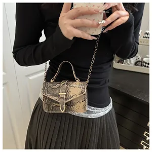 Detail showing snake pattern leather bag with gold chain strap and metal buckle