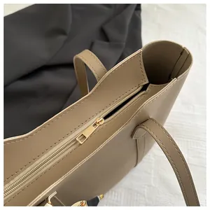 Detail of khaki tote bag with gold metal zipper closure and floral silk scarf charm