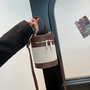 Detail view of contrast stitch bucket bag with brown leather accents and silver hardware