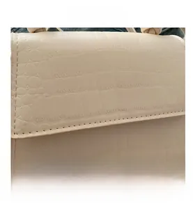 Gros plan sur le motif crocodile beige et les coutures soignées d'un petit sac carré