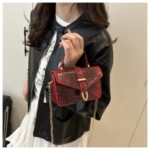 Detail of red snake pattern handbag featuring gold chain and U-shaped metal buckle
