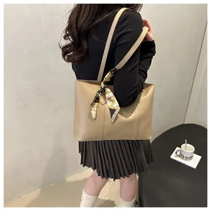 Khaki tote bag with silk scarf detail worn by model in a minimalist modern setting