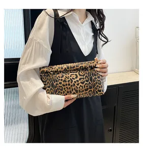 Fashionable leopard print clutch bag with fold-over flap held by model in casual style