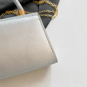 Macro shot of silver textured fabric with golden chain detail on a luxury evening bag