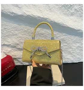 Detail of glitter gold crossbody bag with silver rhinestone bow and metal chain strap