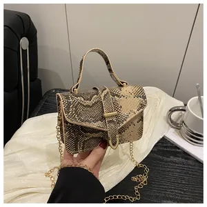 Close-up of snake skin texture and gold U-shaped metal lock on a vintage crossbody bag