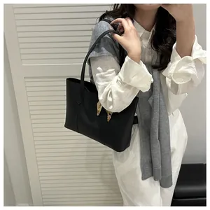 Detail of black leather tote bag with printed silk scarf handle for urban commute