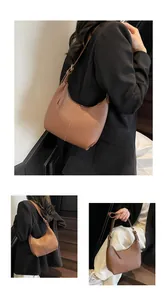 Detail view of brown leather crescent bag with vertical stitching and gold hardware
