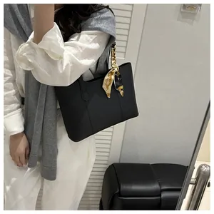 Detail of black leather tote bag with elegant floral scarf on handle worn by model