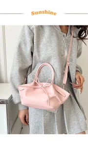 Detailed view of pink bow bucket bag with drawstring, worn by model over a grey hoodie