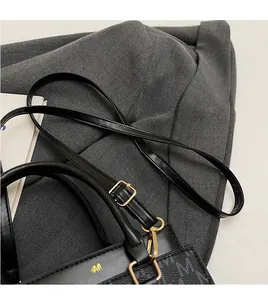 Detail of sleek leather shoulder strap with gold hardware on a printed handbag