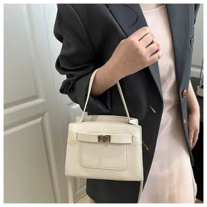 Elegante Frau im grauen Blazer mit cremefarbener Handtasche und goldenem Drehverschluss