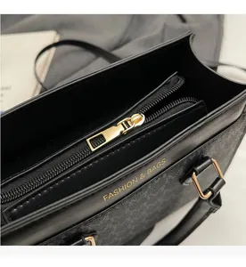Close-up of golden zipper hardware and gold embossed text on black leather handbag