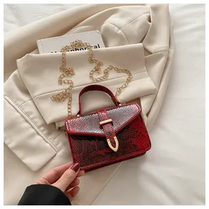 Detailed macro view of red snakeskin texture with gold hardware on crossbody bag