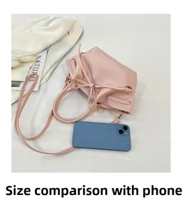 Pink bat bag with drawstring bow detail shown next to a smartphone for size reference