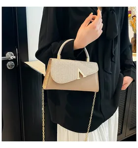 Detailed view of beige handbag with sparkling silver sequins and gold V-shaped buckle