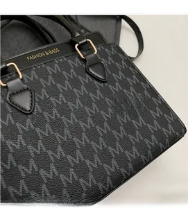 Close-up of black leather handbag with grey M-letter monogram and golden buckles