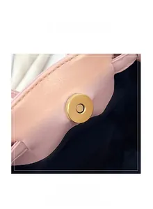 Close-up of golden magnetic buckle on pink pebbled leather handbag with neat stitching