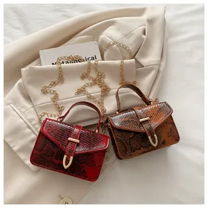 Detail of snake skin texture flap bags in burgundy and brown with gold chain straps