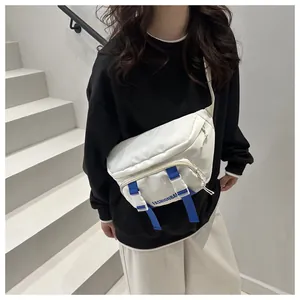 Close-up of white nylon crossbody bag with blue contrast webbing and buckle detail
