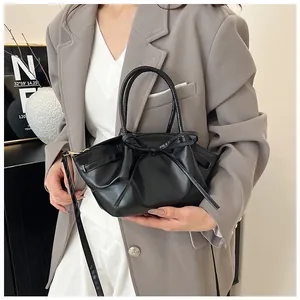 Detail view of the black pleated leather crossbody bag with a decorative bow on a model