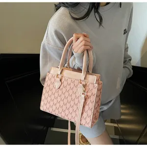 Detail of light pink crossbody bag with fashion letter print and sleek top handle