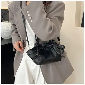 Detail of black trapezoid bag featuring pleated texture and bow decoration