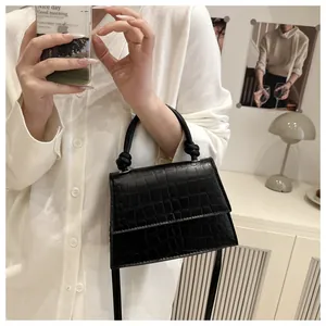 Vue détaillée du sac à main noir texture crocodile avec poignée nouée et rabat élégant