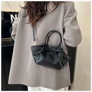 Detail of black mini crossbody bag featuring decorative knot and sleek leather finish