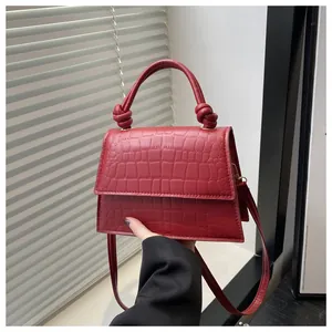 Détail du sac à main rouge foncé à motif crocodile avec une poignée nouée élégante