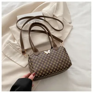 Detail of vintage patterned Boston bag with white butterfly charm on blazer background