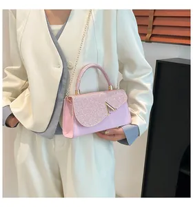 Detail of pink rhinestone handbag with gold V logo shown on a cream outfit