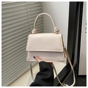 Détail de la texture crocodile blanc cassé et de la poignée nouée sur le sac