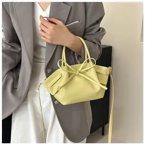 Detail of light yellow bat bag featuring a large bow and soft synthetic leather texture