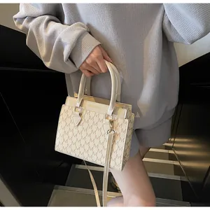 Detail of vintage beige monogram crossbody bag worn on shoulder by model in urban setting