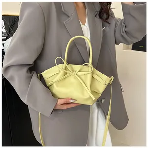 Detailed view of the yellow bat-shaped handbag with a decorative bow and soft faux leather texture
