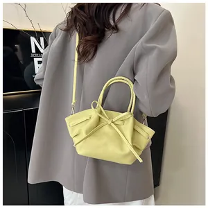 Detail view of the pale yellow bat bag featuring a large bow and soft leather pleated sides