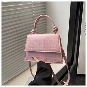 Détail du sac à main rose gaufré crocodile avec poignée nouée et bandoulière fine